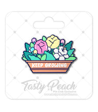Load image into Gallery viewer, An enamel pin with a design of colorful flowers and the text 'KEEP GROWING' on a white backing card, labeled as a 'Tasty Peach' exclusive.
